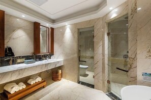 Un baño moderno con paredes de mármol, ducha con cerramiento de vidrio y tocador de madera con espejo.