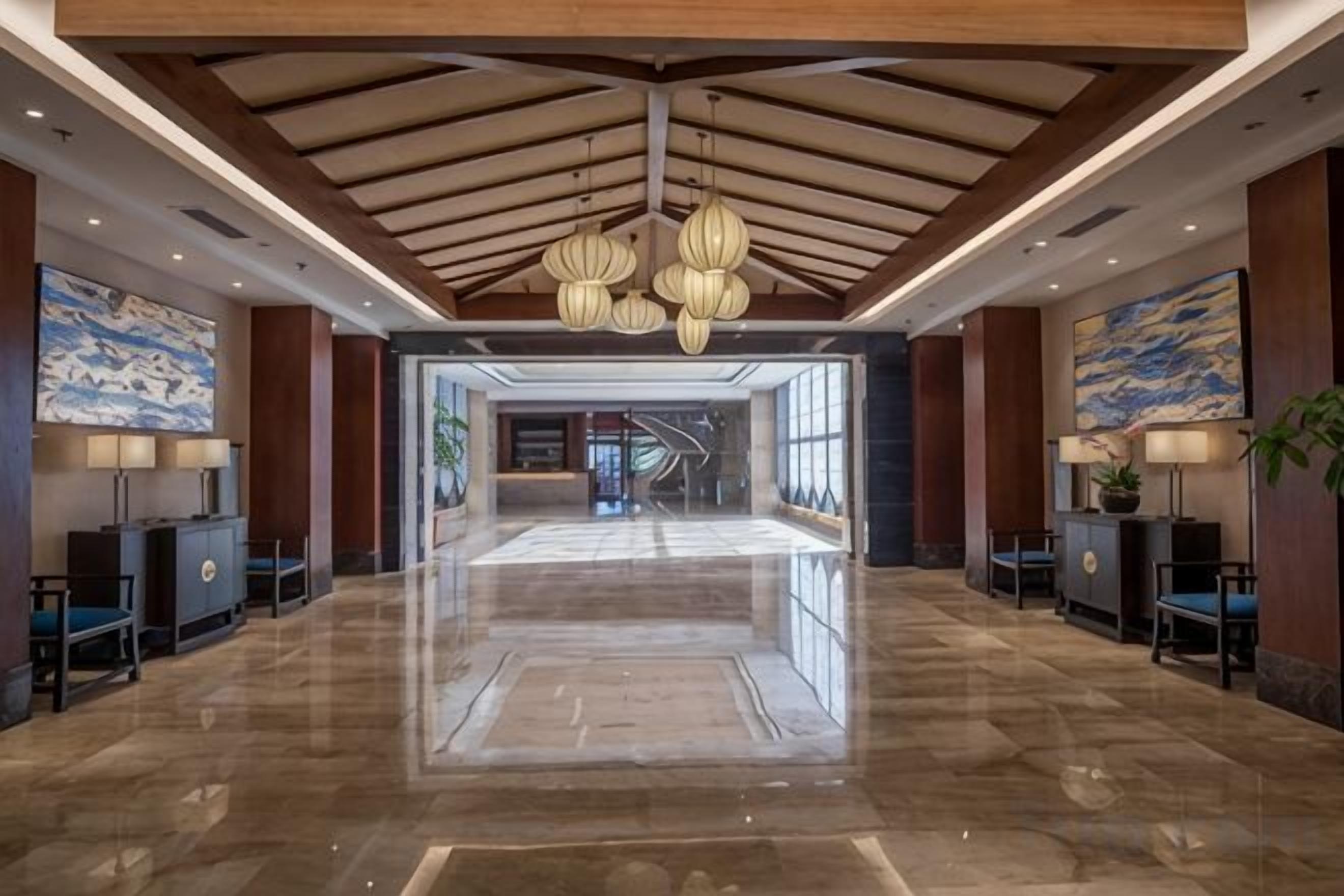 A spacious lobby with a high ceiling, polished marble floors, and modern lighting fixtures.