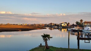 Um cais com barcos atracados, uma pequena palmeira e edifícios ao fundo.