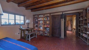 A room with a bed, a desk, a bookshelf, and a view through a window. - Canyon Getaway- Courtyard -Canyon Rd & Plaza -1BR (Santa Fe)