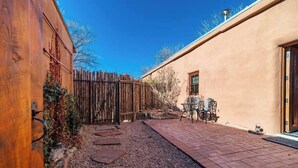 A patio area with a gravel path, a wooden fence, and a table with chairs. - Canyon Getaway- Courtyard -Canyon Rd & Plaza -1BR (Santa Fe)