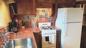 A kitchen with wooden cabinets, a gas stove, a sink, and a refrigerator. - Canyon Getaway- Courtyard -Canyon Rd & Plaza -1BR (Santa Fe)