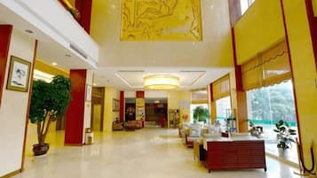 A hotel lobby with a reception desk, seating area, and a large artwork on the wall.