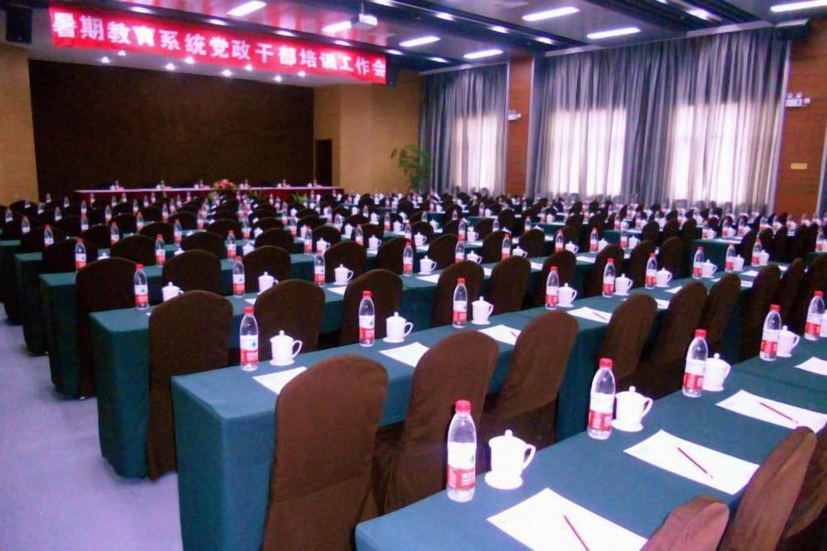 A conference room with rows of tables, chairs, and water bottles.