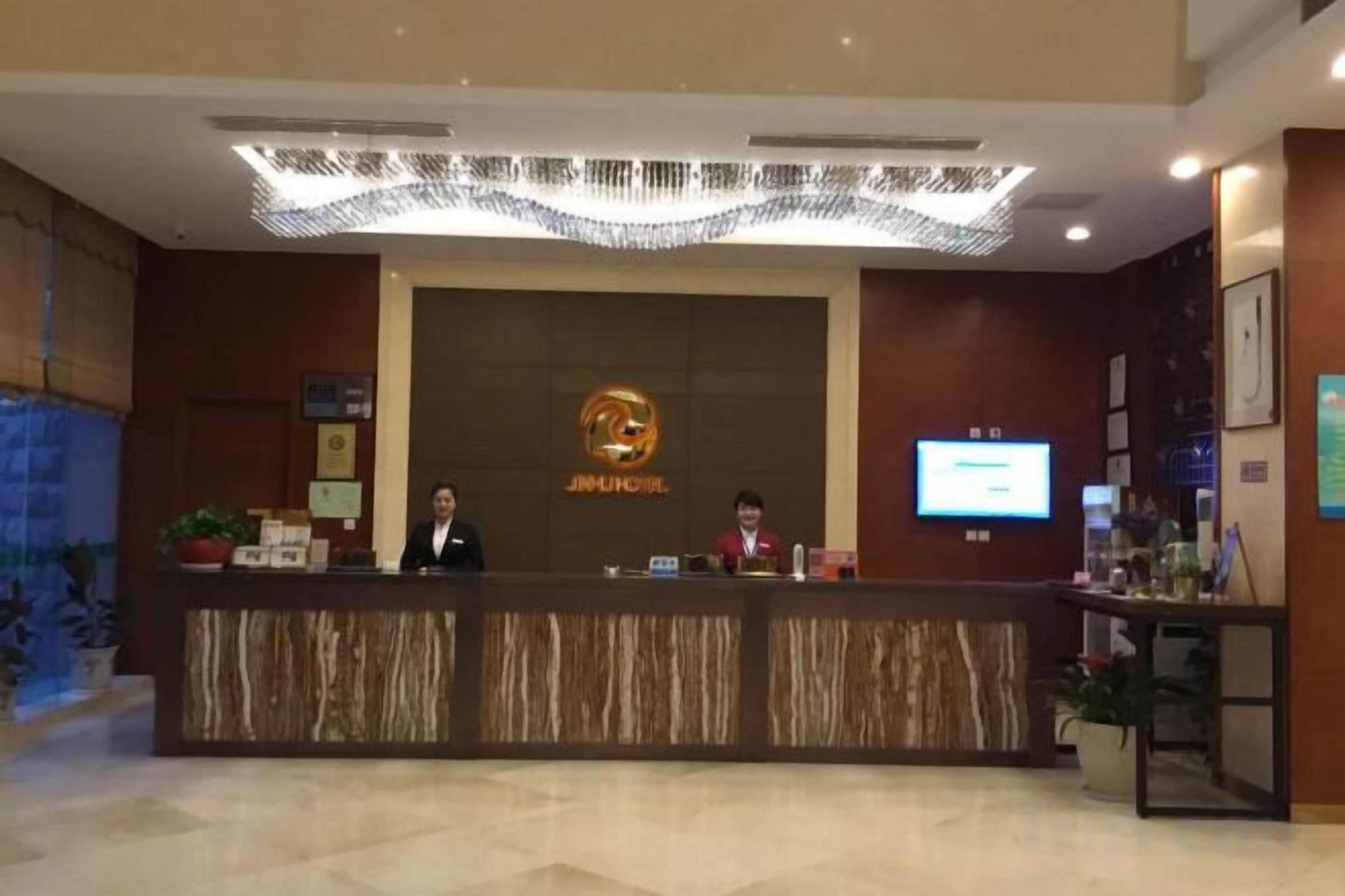 A reception desk with a digital screen, a logo, and a reception area with a plant.