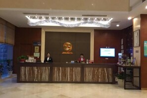 A reception desk with a digital screen, a logo, and a reception area with a plant. - Jinhu Hotel (Wuxi)