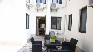 A patio with a table and chairs, a potted plant, and air conditioning units on the wall. - Jinhu Hotel (Wuxi)