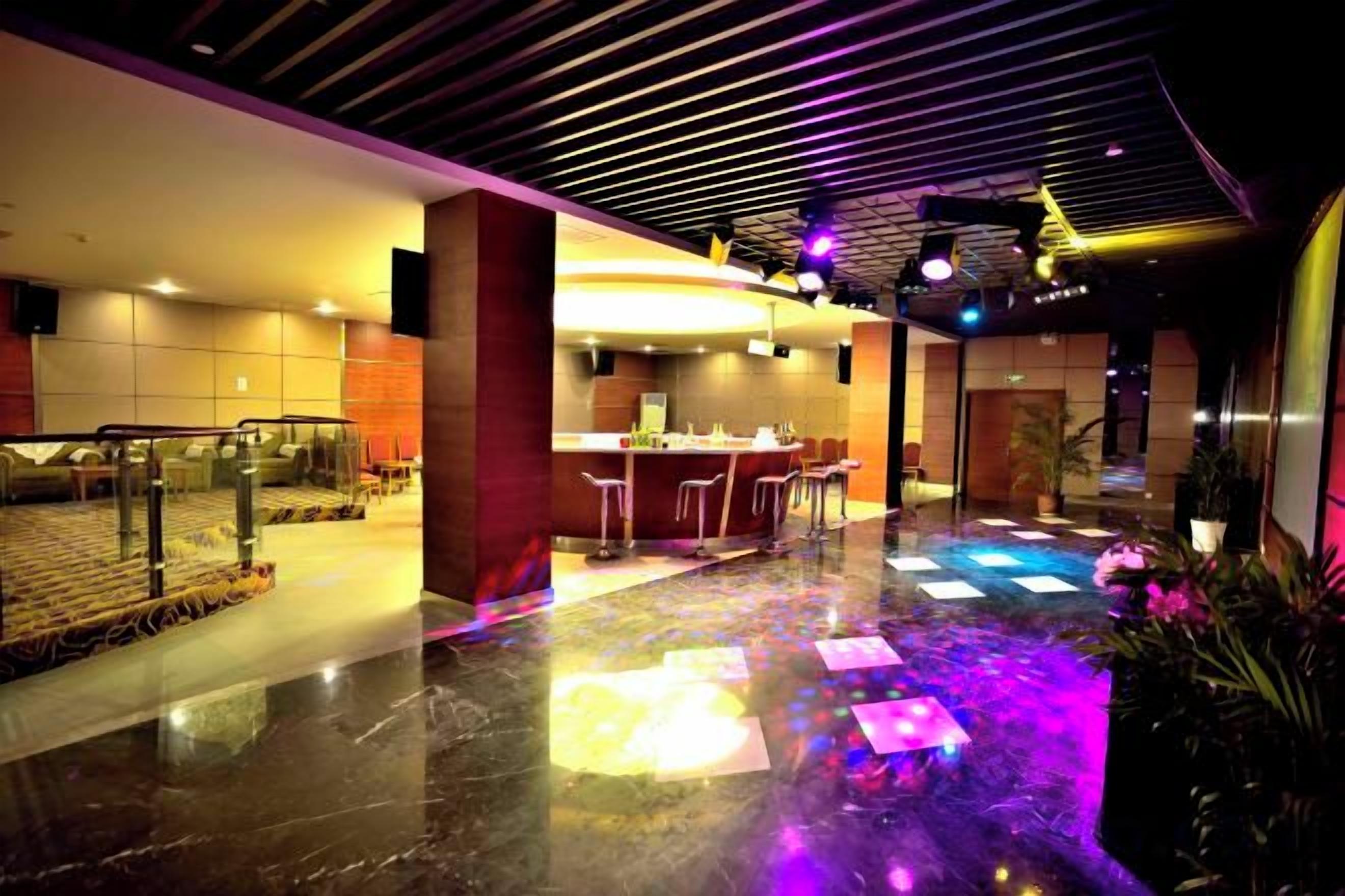 A hotel lobby with a bar area, seating, and a staircase.
