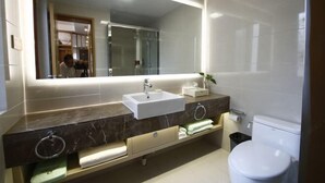 A modern bathroom with a large mirror, a white sink, a toilet, and a marble vanity with towel racks. - Jinhu Hotel (Wuxi)