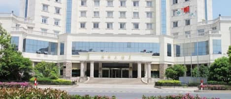 A multi-story hotel with a central entrance, large windows, and a flag on the right side.