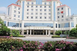 A multi-story hotel with a central entrance, large windows, and a flag on the right side. - Jinhu Hotel (Wuxi)