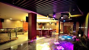 Eine moderne Hotelhalle mit Marmorboden, einer Rezeption und einer Bar.