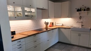 A modern kitchen with white cabinetry, a wooden countertop, and a built-in sink. - Family home in Provence with swimming pool (Noves)
