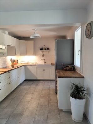 A modern kitchen with white cabinets, a wooden countertop, a sink, and a potted plant. - Family home in Provence with swimming pool (Noves)