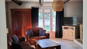A living room with a brown leather sofa, a wooden coffee table, and a television on a wooden cabinet. - Family home in Provence with swimming pool (Noves)