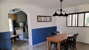 A dining area with a wooden table and chairs, a blue accent wall, and a black pendant light. - Family home in Provence with swimming pool (Noves)