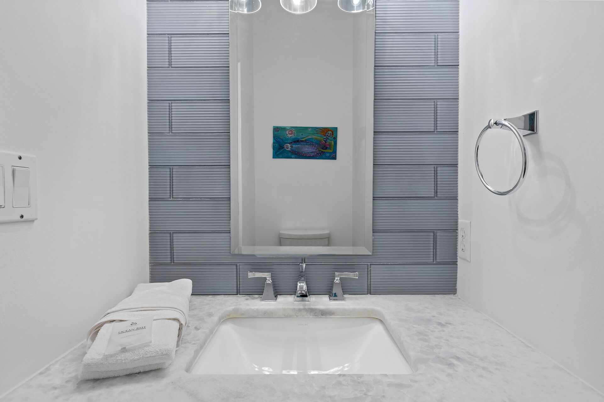 Een moderne badkamer met een grote spiegel, een wastafel en een handdoek op het aanrecht.