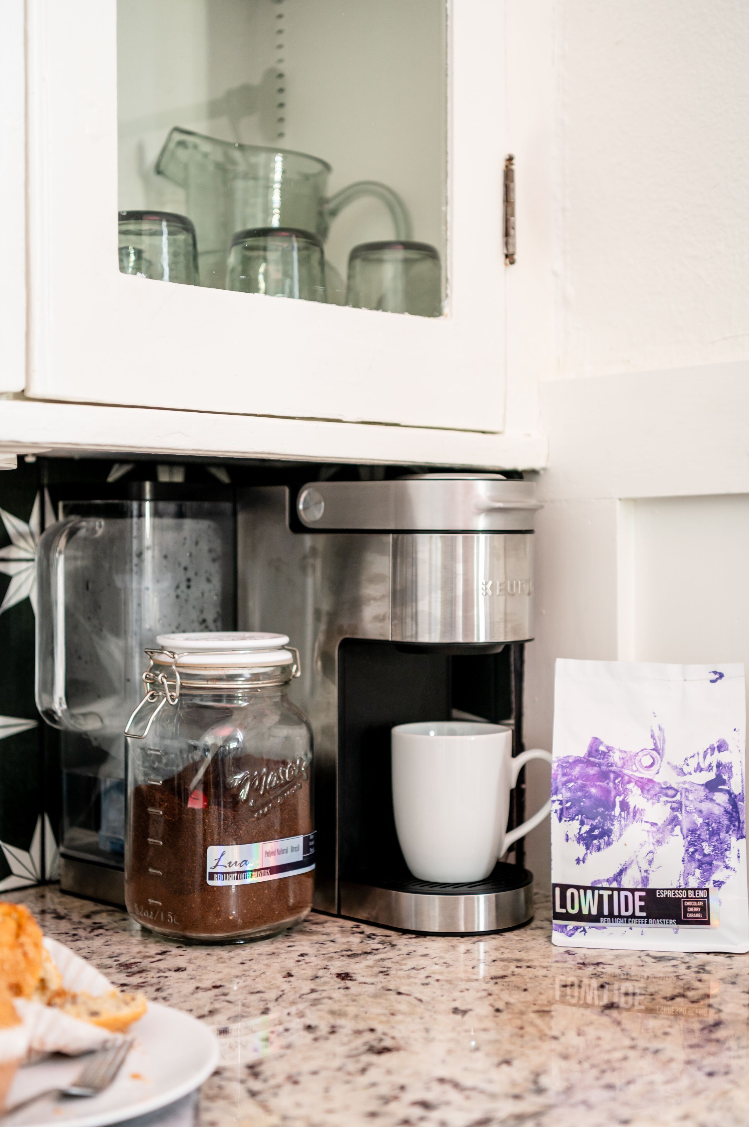 Una cucina con una macchina da caffè, un barattolo di caffè e cialde per caffè.
