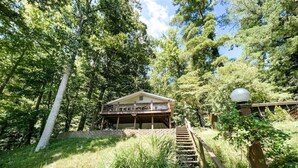 A wooden cabin with a balcony, surrounded by trees and a stone wall. - Lakefront  Hot tub. Amazing views. 35 min to Indy (Martinsville)
