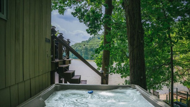 A hot tub with a view of a lake and a wooden staircase leading to a deck. - Lakefront  Hot tub. Amazing views. 35 min to Indy (Martinsville)