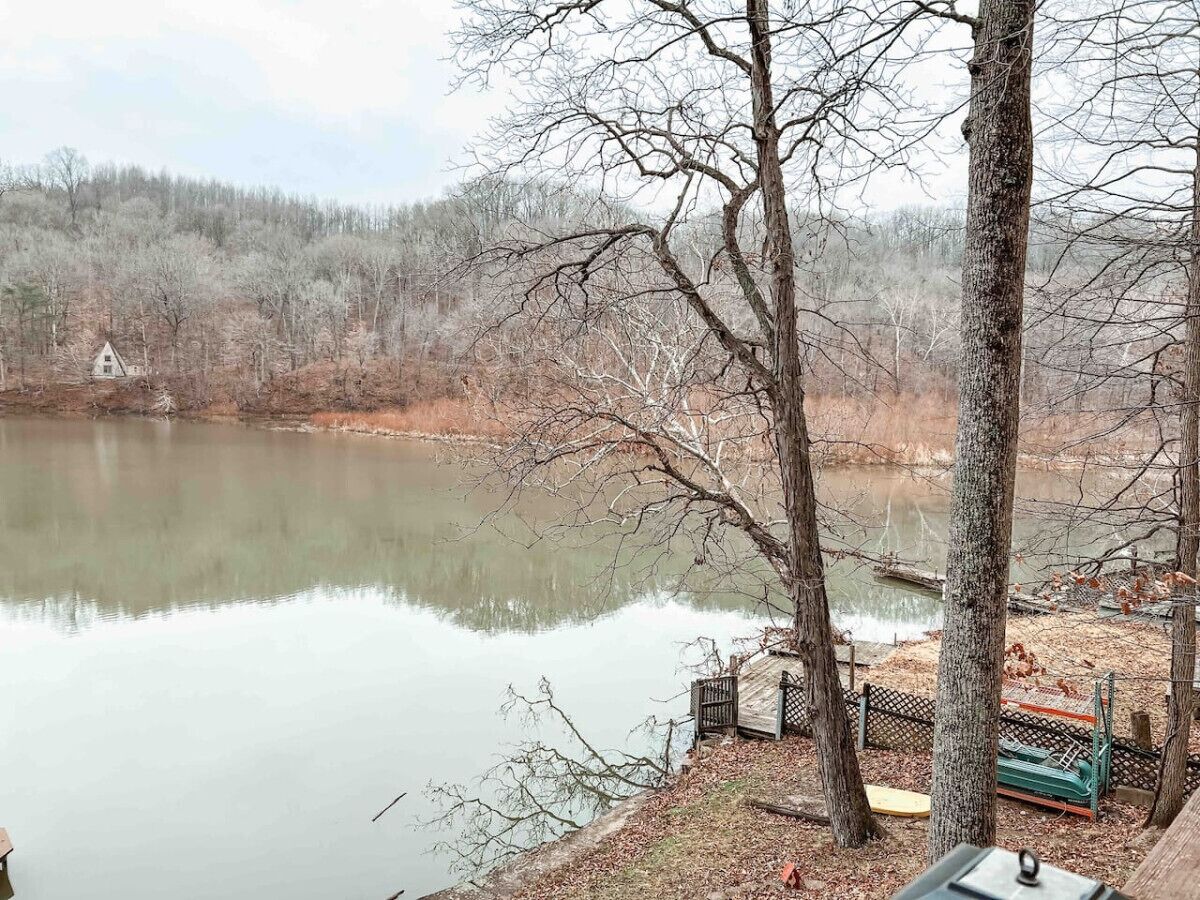 Ein ruhiger See mit einer Holzsteganlage und einem kleinen Haus im Hintergrund.