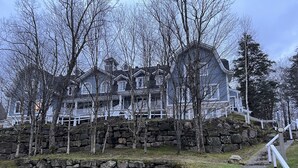 A large, multi-story building with a stone retaining wall and a staircase leading up to it. - Supérieur HBC themed condo in Tremblant village (Mont-Tremblant)