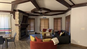 A living room with a stone fireplace, wooden beams, a red bean bag, and a sofa. - Supérieur HBC themed condo in Tremblant village (Mont-Tremblant)