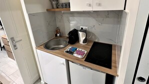 A compact kitchen with a sink, a coffee maker, a kettle, and a small refrigerator. - Apartment Gutenberg 3 (Paris)