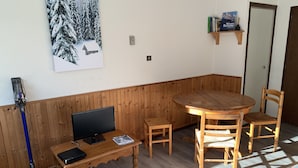 Une pièce chaleureuse avec une table et des chaises en bois, un téléviseur et une bibliothèque remplie de livres.