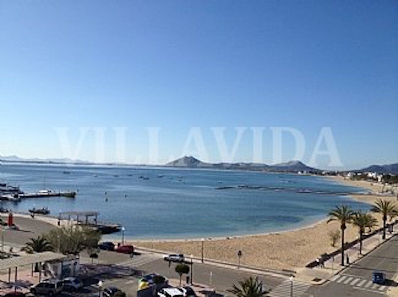 Une vue sur la côte, avec une plage, des bateaux et un ciel dégagé.