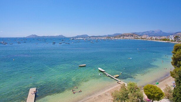 A coastal area with clear blue waters, boats, and a beach. - Seafront Penthouse Marina Apartment (Port de Pollença)