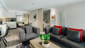 A modern living room with a grey sofa set, a coffee table with a plant, and a dining area with a table and chairs.