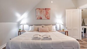 A neatly made bed with a white duvet, two bedside lamps, and a painting on the wall. - 4 Units! Mins to Downtown&Dining - Dauphin Darling (Mobile)