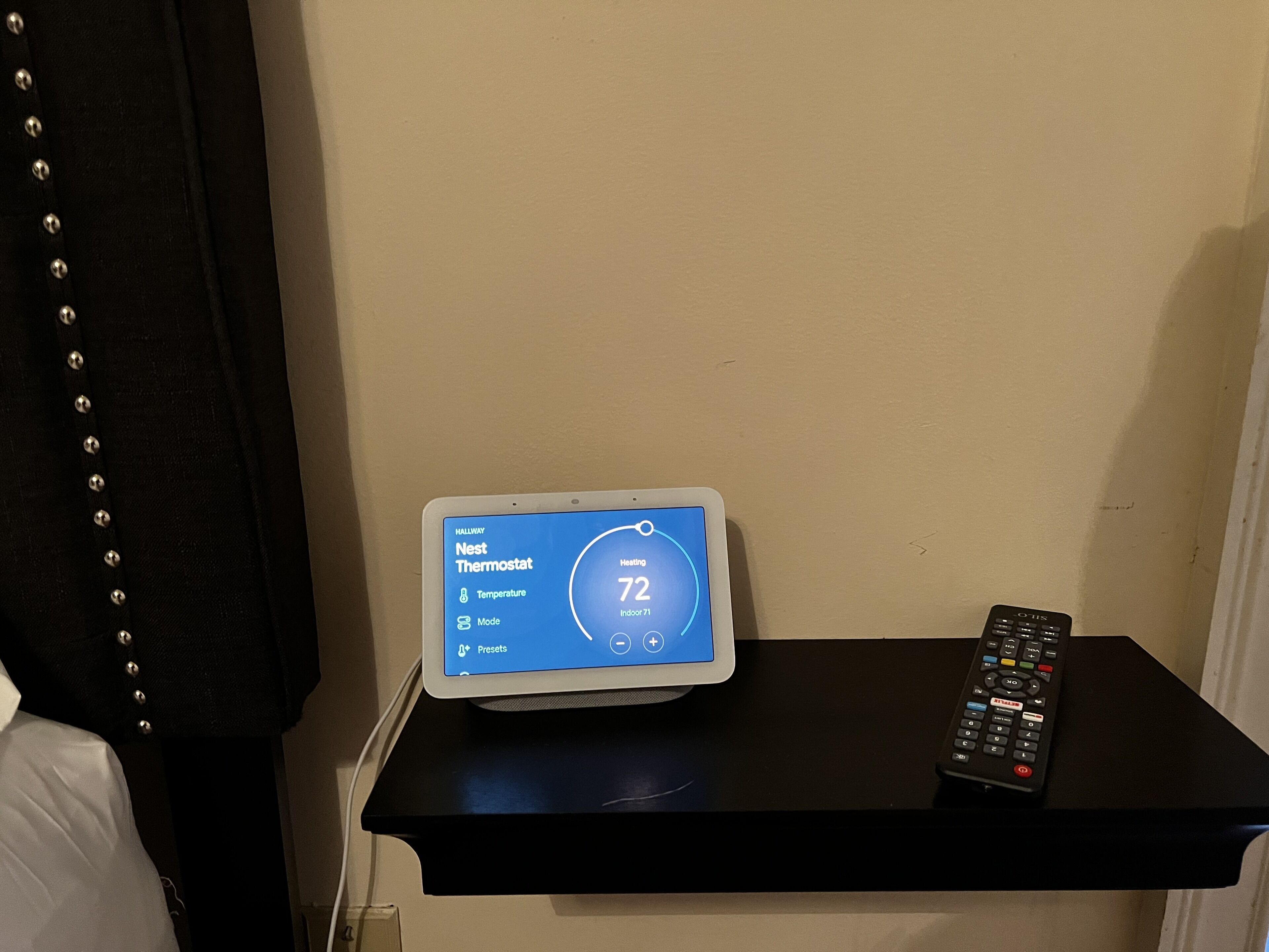 A Nest Thermostat displaying a temperature of 72 degrees Fahrenheit on a black wall-mounted panel.