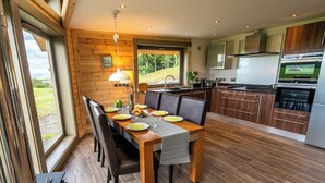 Een moderne keuken met houten kastjes, een eethoek met een tafel gedekt voor vier personen, en een groot raam met uitzicht op een schilderachtig panorama.