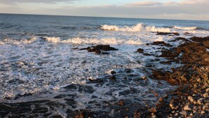 Une côte rocheuse où les vagues s’écrasent contre les rochers.