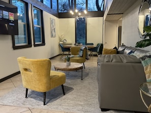 Un salon moderne comprenant un canapé, des fauteuils et un coin repas avec une table et des chaises.