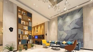 Eine moderne Lobby mit Sitzgelegenheit, einem Holzregal und einer Wand mit geometrischem Muster.