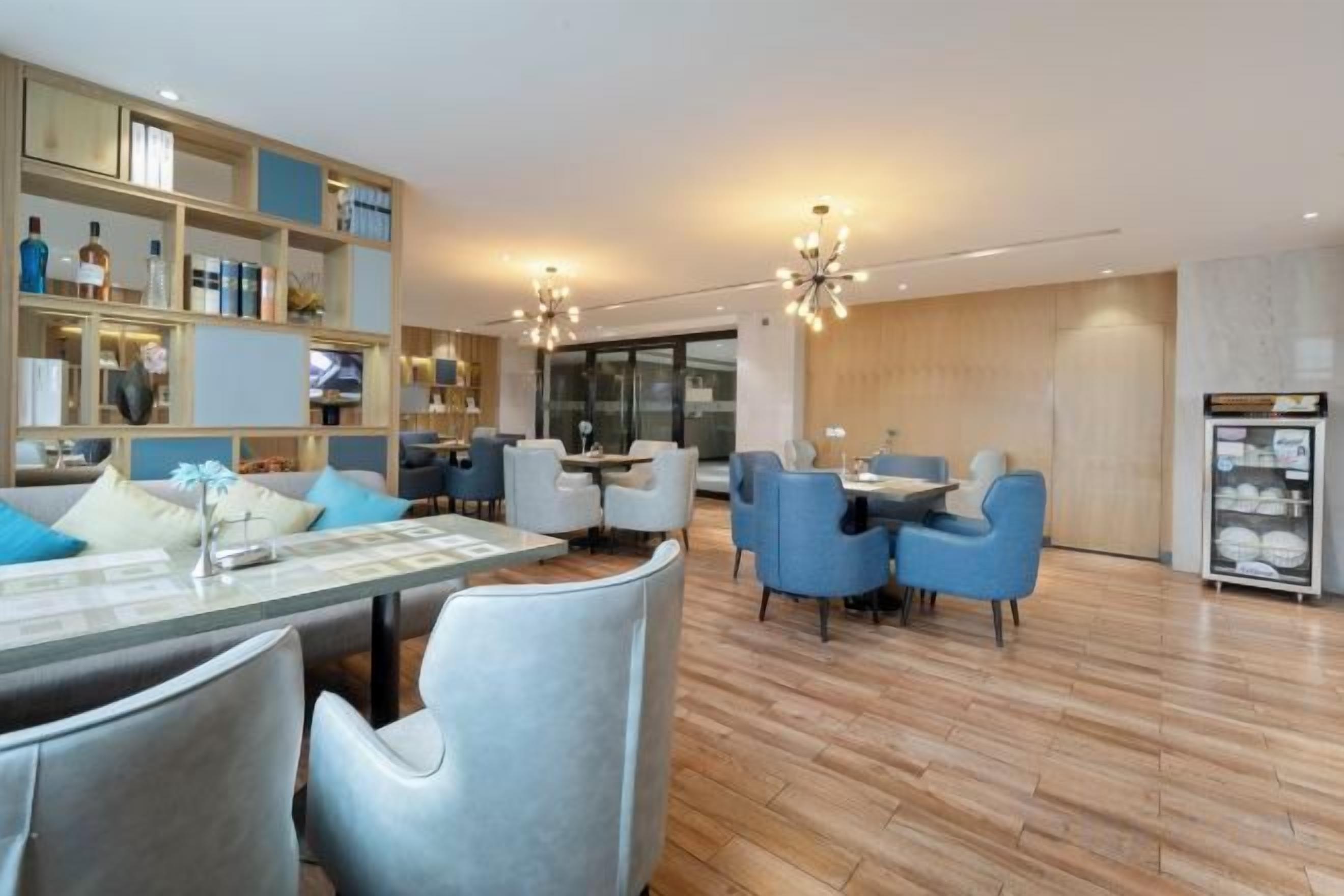 A modern hotel lobby with a dining area, seating arrangements, and a reception desk.