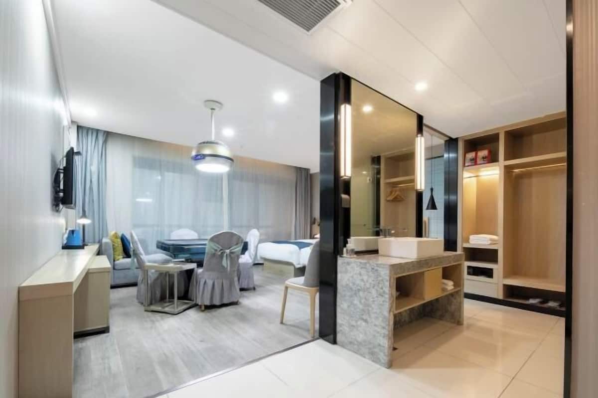 Une chambre d’hôtel moderne dotée d’un coin repas, d’un grand miroir et d’une armoire intégrée.