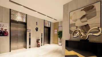 Un hall de hotel con una recepción, ascensores y una gran obra de arte abstracta en la pared.