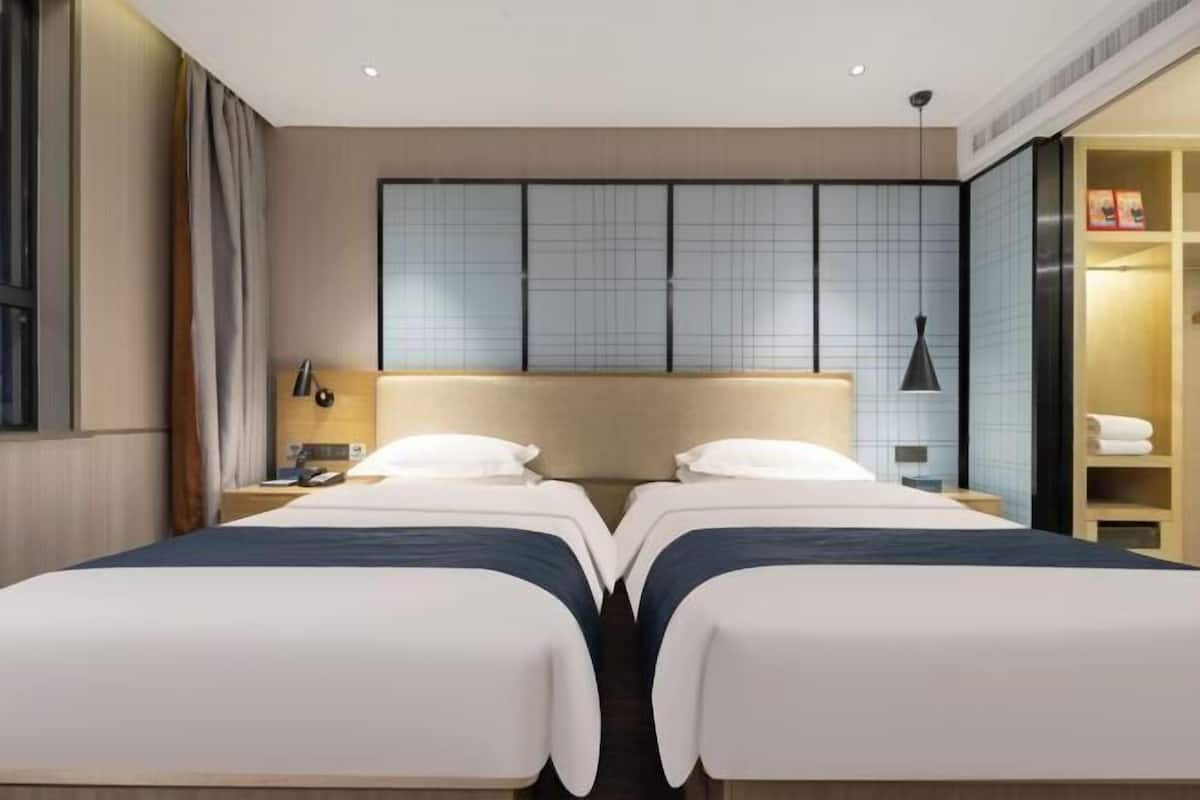 Une chambre d’hôtel avec deux lits, une grande fenêtre et une vue sur le paysage urbain.