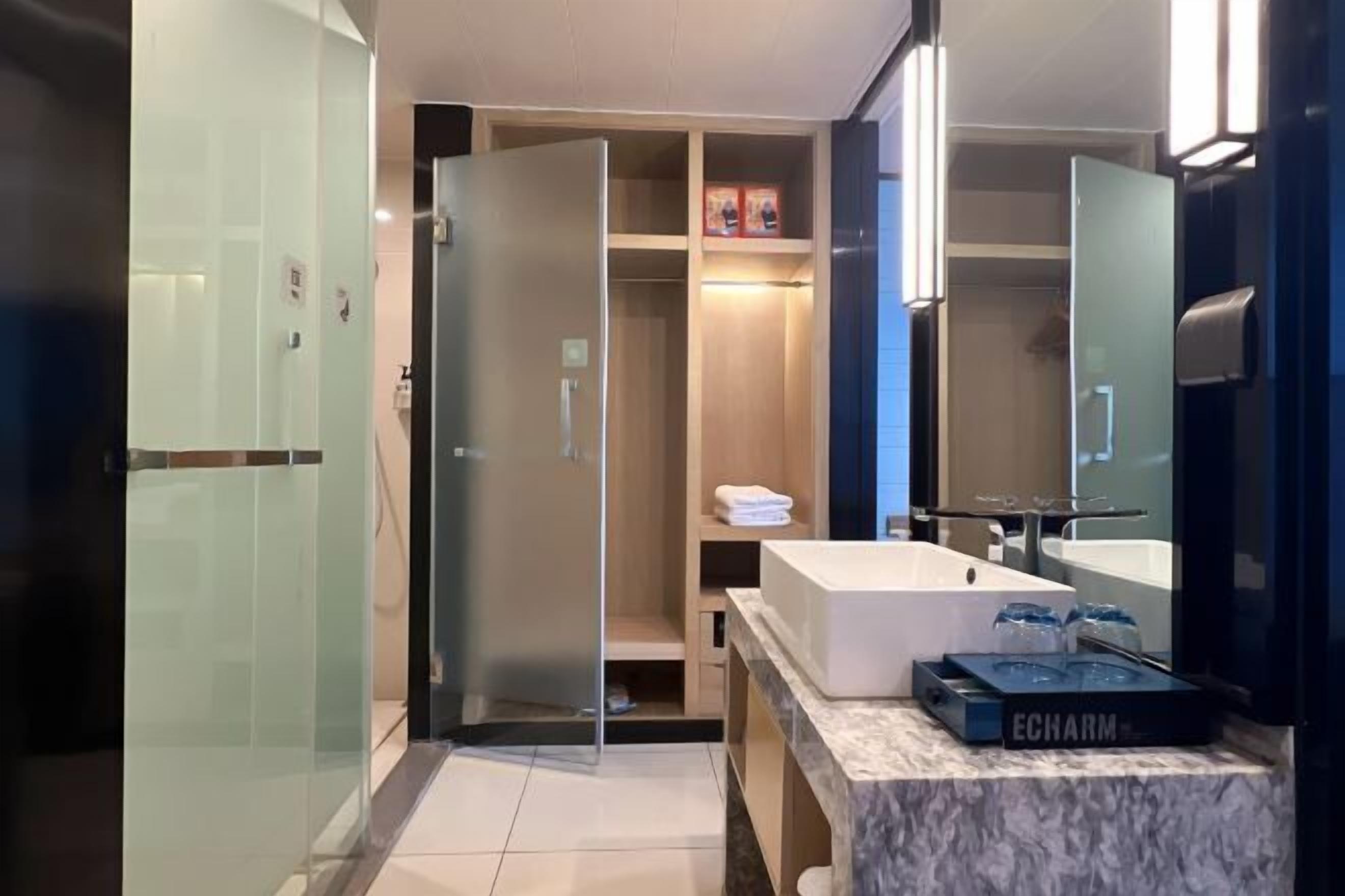 A modern bathroom with a glass shower enclosure, a white sink, and a vanity with a marble countertop.