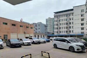 Un parking avec plusieurs voitures et des bâtiments en arrière-plan.