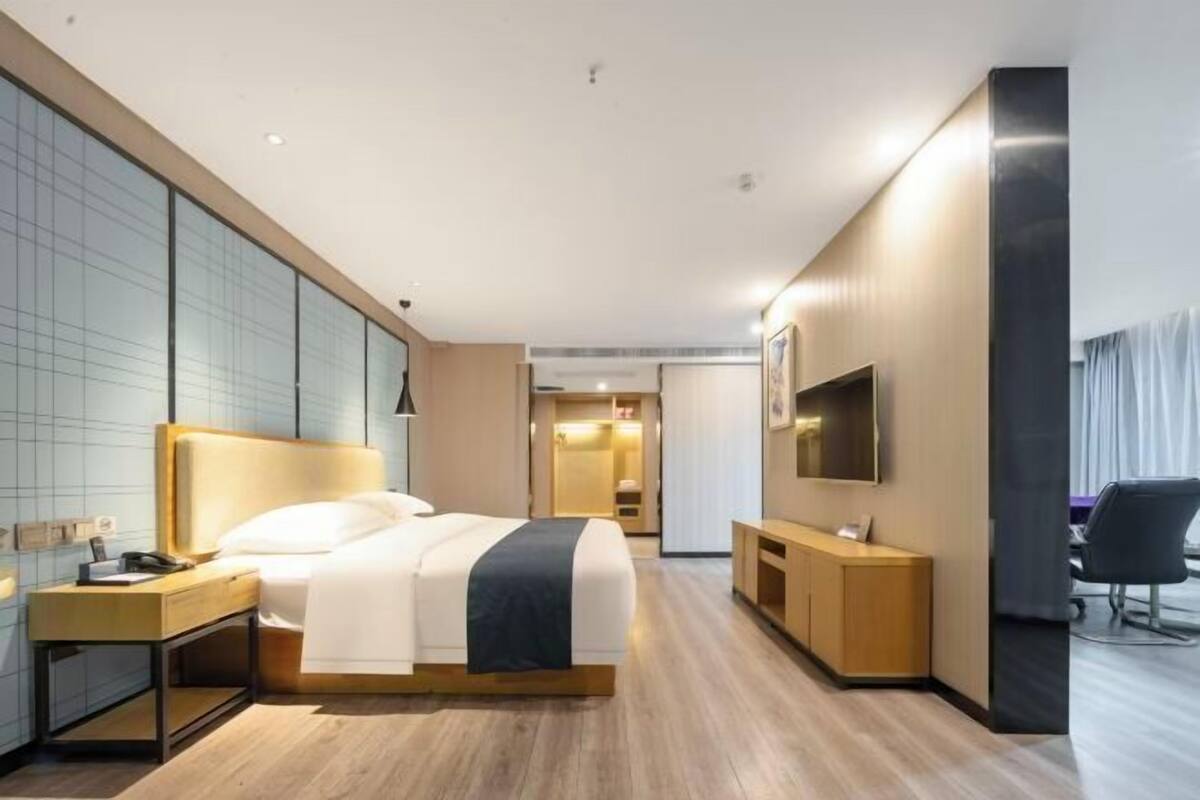 Une chambre d’hôtel moderne dotée d’un grand lit, d’un bureau, d’une télévision à écran plat et d’un coin salon.
