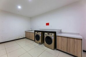 Un área de lavandería con dos lavadoras, un lavabo y una encimera.