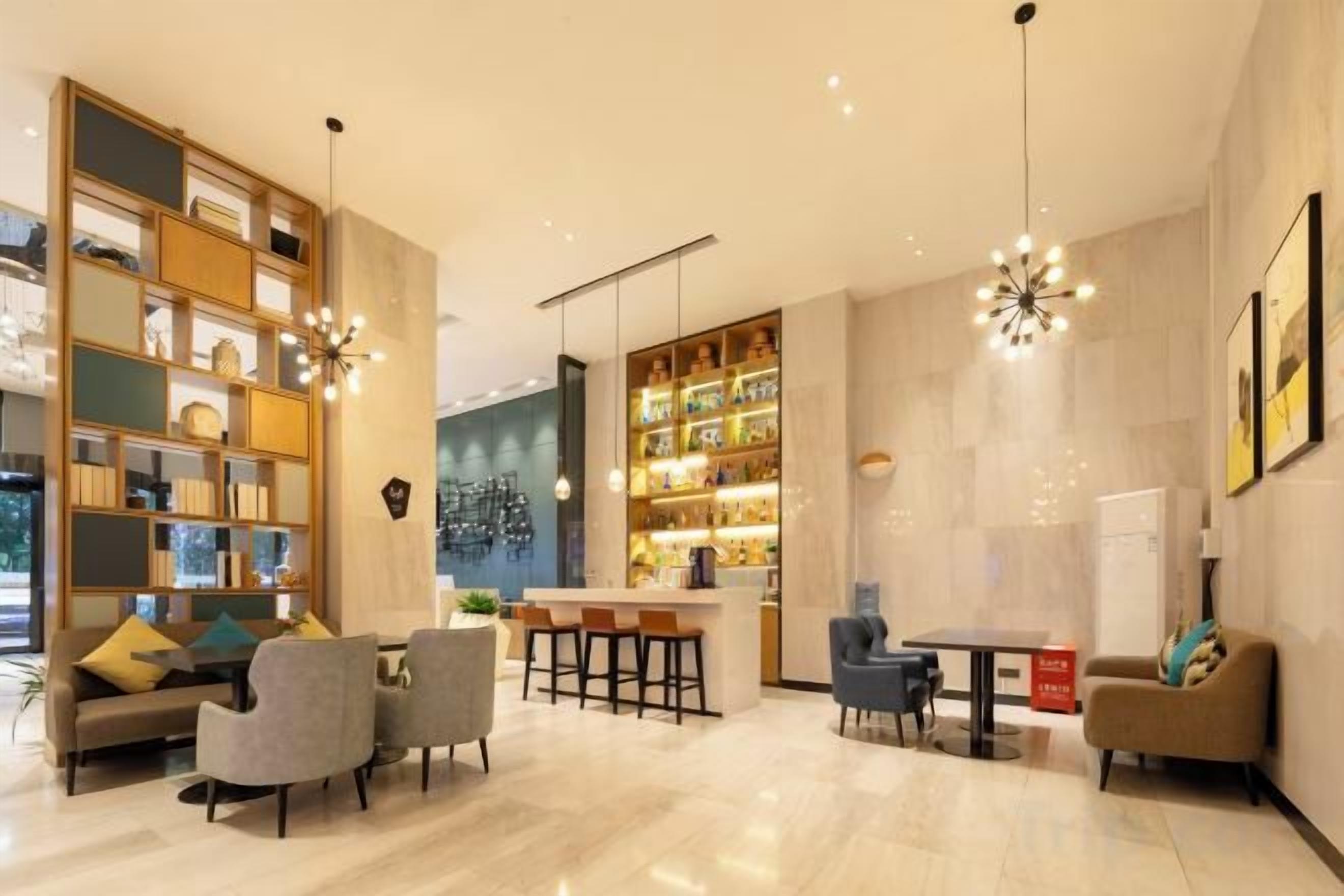 Un moderno vestíbulo de hotel con una zona de estar, un bar y una estantería.