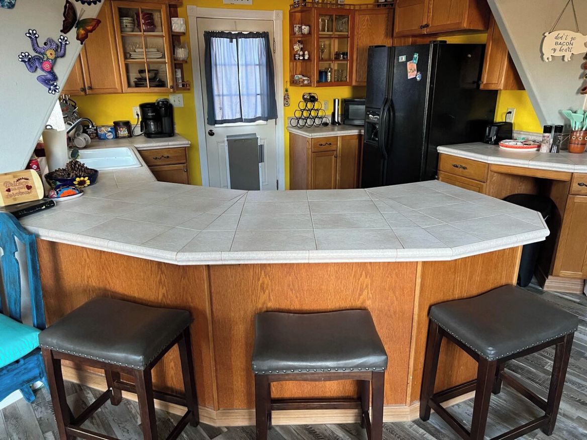 A kitchen with a central island, wooden cabinets, a refrigerator, and a microwave.