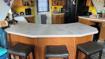 A kitchen with a central island, wooden cabinets, a refrigerator, and a microwave.