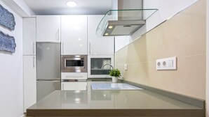 Una cocina moderna con armarios blancos, electrodomésticos de acero inoxidable y salpicadero de vidrio.